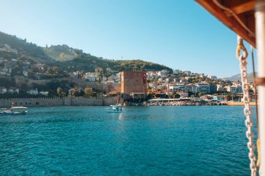 Ele geçirilmiş bir manzara, heybetli, sakin, ışıl ışıl sulara ve bereketli tepelere bakan tarihi bir kuleyi gözler önüne seriyor.