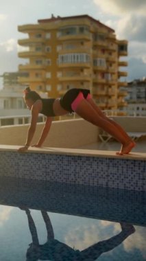 Mutlu bir kadın, arka planda çarpıcı modern mimarisi olan güzel bir havuz kenarında sıcak güneşin tadını çıkarır.