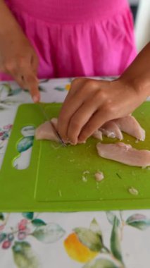 Bir insan canlı yeşil bir kesme tahtasıyla tavuğu ustalıkla keser ve mutfak uzmanlığını gösterir.