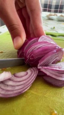 Yetenekli bir şef, parlak kırmızı bir soğanı, rengarenk ve canlı bir kesim tahtasıyla ustalıkla dilimliyor.