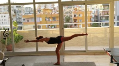 Odaklanmış ve tamamen meşgul bir birey şehir manzaralı bir arka planla kapalı bir fitness gösterisi sergiliyor.