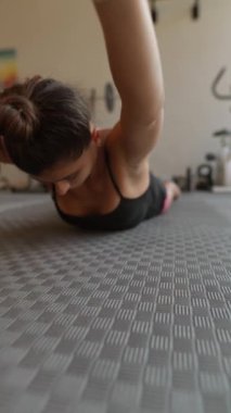 Dokulu bir spor paspası üzerinde spor yapan bir kadın yoğun bir şekilde odaklanmış ve son derece kararlıdır.