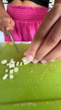 Canlı bir kesim tahtasında çeşitli taze, renkli sebzeleri ustalıkla doğrayan ellerin detaylı bir yakın çekimi.