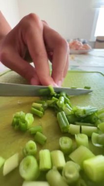 Yetenekli bir el, parlak ve davetkar bir mutfakta taze soğan doğruyor.