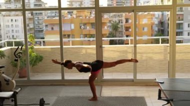 Şık ve şık bir kapalı mekan ortamında dinamik bir esneme hareketleri yapan konsantre bir insan.