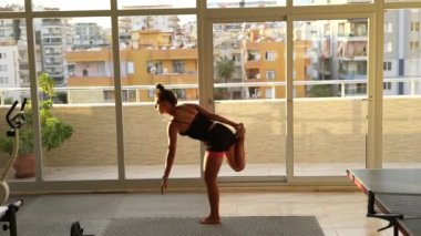 Bir dansçı zarif bir şekilde şehrin gökyüzü manzarasıyla övünen modern ve parlak bir dairede geriniyor.