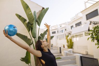 Neşeli ve hevesli genç bir kadın canlı yemyeşil bahçelerle çevrili açık havada bowlingden zevk alıyor.