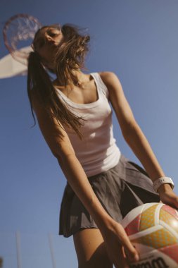 Voleybol oyuncusu dinamik hareket halinde, canlı mavi bir gökyüzü zeminine karşı atletizm sergiliyor.