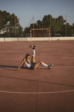 Etkileyici bir atlet, güneşli bir açık hava spor sahasında esnek ve atletizm sergiliyor.