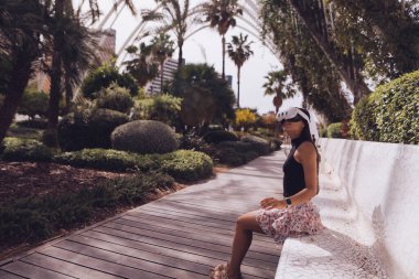 Bir kadın yemyeşil yemyeşil bir bankta otururken sakin ve huzurlu bir anın tadını çıkarıyor.