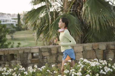 Bir kadın yemyeşil bir alanda koşmaktan ve huzurlu bir park ortamında çiçek açmaktan zevk alır.