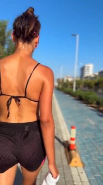 Güneşli bir günlük gezintiden hoşlanan bir insan, aktif bir yaz yaşam tarzını canlı şehir arkaplanıyla somutlaştırıyor..