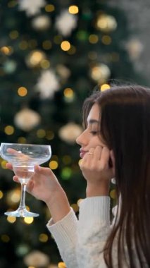 Bir kadın, Noel için dekore edilmiş rahat bir atmosferle çevrili iken şenlikli bir içeceği yudumlamaktan zevk alır.