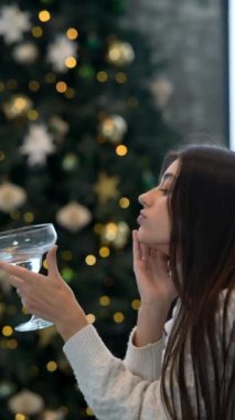 Genç bir kadın, güzel dekore edilmiş bir Noel ağacıyla çevrili güzel bir içecekle keyifli bir anın tadını çıkarır.