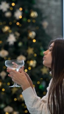 Bir kadın, büyüleyici Noel süslemeleriyle çevrili bir şekilde içkisini yudumlarken huzurlu bir andan zevk alır.