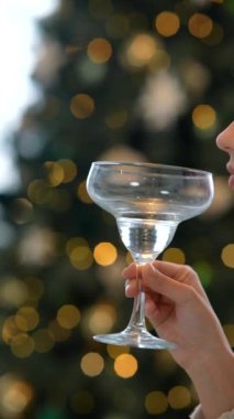 Kutlama için zarif bir kokteyl kadehi kaldırılır ve arka planda parıldayan güzel şenlik ışıkları yanar.