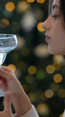 Şenlikli ışıkların arasında ferahlatıcı bir içkinin tadını çıkaran bir kadın, bayram zarafetini ve neşeli beklentilerini yakalıyor.