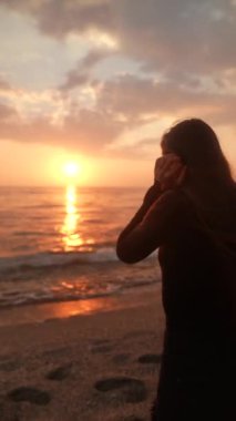 Deniz kenarında sakin ve huzurlu bir anın tadını çıkarırken aynı zamanda suda gün batımının nefes kesici yansımasını yakalıyor.