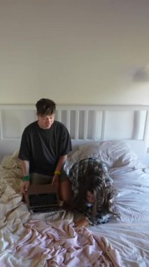 Genç bir çift, bir yatakta oturup birlikte dizüstü bilgisayarla uğraşırken samimi ve samimi bir anı paylaşıyor.