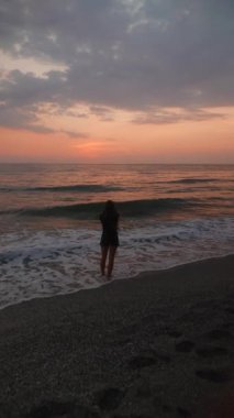 Huzurlu bir siluet canlı ve çarpıcı bir günbatımına karşı duruyor bu güzel sahil manzarasının tadını çıkarırken