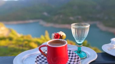 Resimli bir dağ gölünün çarpıcı manzarasına karşı sakin bir kahve ve tatlı düzenlemesi.