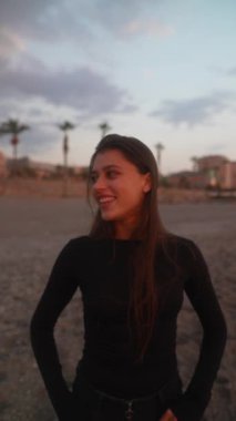 Genç bir kadın, huzurlu günbatımında, kumsalda güzel bir anda neşe bulur, mutlu ve rahat hisseder.