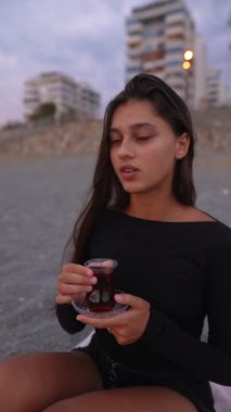 Gün batımında sıcak çayını yudumlayan bir kadının huzurlu ve huzurlu anı.