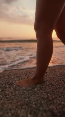 Huzurlu bir gün batımı sahnesi. Huzurlu bir yalınayak sahnesi. Kıyı boyunca yürürken gel-git gelir ve gider.