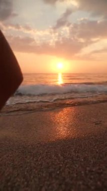 Huzurlu bir sahil boyunca sakin bir şekilde yürüyen ve huzuru yakalayan bir insanın nefes kesici ve huzurlu bir gün batımı görüntüsü.