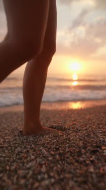 Huzurlu ve huzurlu bir an. Güzel bir günbatımında sahilde usulca yürüyen ayakları yakalıyor.