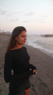 Gün batımında zarif bir şekilde sahilde duran bir kadının huzur ve huzur dolu bir anı.