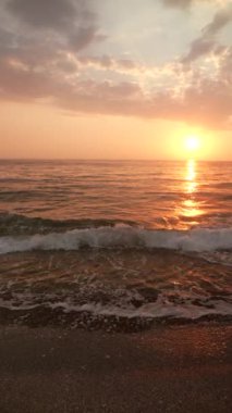 Huzurlu bir kadın silueti. Okyanus kıyısındaki güzel günbatımını seyrediyor. Huzurlu ve huzurlu anları yakalıyor.