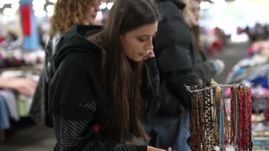 Genç bir kadın, benzersiz aksesuarlarla dolu işlek bir markette canlı bir mücevher dizisini keşfediyor.