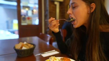 Ilık bir restoranda aşçılık deneyimine dalmış genç bir kadın yemeğinin her lokmasının tadını çıkarıyor.