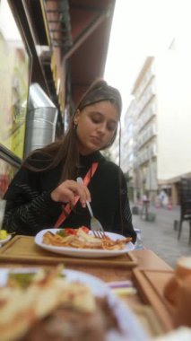 Canlı bir açık hava ortamında makarnanın tadını çıkaran bir kadın mutfak neşesinin özünü tamamen yakalıyor.