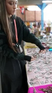 Bir kadın, canlı ve hareketli bir pazarda sergilenen etkileyici bir klasik mücevher dizisini dikkatlice inceliyor.