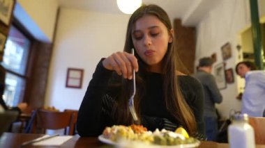 Sıcak ve davetkar bir restoranda yemeğin tadını çıkaran ve tadını çıkaran bir kadını yakalamak.