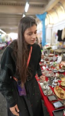 Genç bir kadın, büyüleyici bir açık hava pazarında çeşitli eşsiz vintage ürünleri keşfetmekten zevk alır.