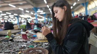 Meraklı genç bir kadın canlı bir yerel markette büyüleyici ve zarif mücevherleri dikkatle inceliyor.