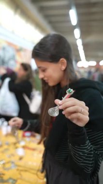 Genç bir kadın renkli bir pazarda el yapımı güzel mücevherleri zevkle keşfediyor, eşsiz bir yaratıcılık sergiliyor.