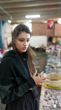 Genç bir kadın, canlı el sanatlarıyla dolu hareketli bir pazarda gururla güzel bir yüzük sergiliyor.