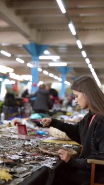 Genç bir kadın, canlı bir pazarda eşsiz ve göz alıcı nesnelere rastlar.