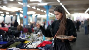 Bir kadın klasik bir markette kıyafet seçeneklerini inceliyor, şık moda tercihlerini sergiliyor ve zevklerini yansıtıyor.