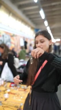 Bir kadın canlı bir yerel markette sergilenen güzel el yapımı mücevherleri dikkatle inceliyor.