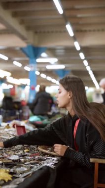 Genç bir kadın, hareketli bir pazarda yaratıcılığı ve zanaatkarlığı ön plana çıkaran çeşitli el sanatları ürünlerini yakından inceliyor.