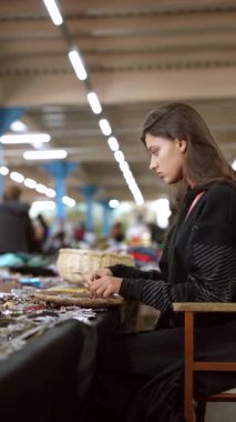 Bir kadın canlı bir pazarda göz kamaştırıcı mücevherleri inceliyor, canlı ve hareketli bir atmosfer sergiliyor.