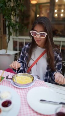 Lezzetli kremalı makarnanın tadını çıkaran şık, genç bir kadın hem rahat hem de davetkar bir restoran ortamının tadını çıkarıyor.