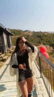 Şık bir kadın, neşe ve coşku saçan canlı kırmızı balonlarla zarif bir şekilde dışarıda poz verir.