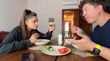 Neşeli bir çift, sıcaklığı, yakınlığı ve iyi yiyecekleri vurgulayarak, besleyici bir kahvaltıyı keyifle paylaşıyor.