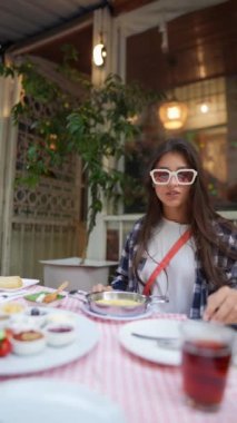 Zarif genç bir kadın, enfes yemekler ve enfes bir ambiyansla çevrili büyüleyici bir restoranda yemek yiyor.